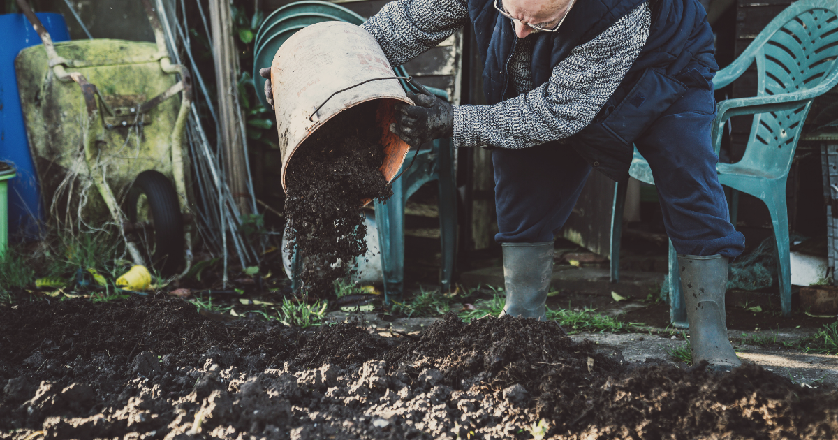 man adding bucket of soil amendments to soil